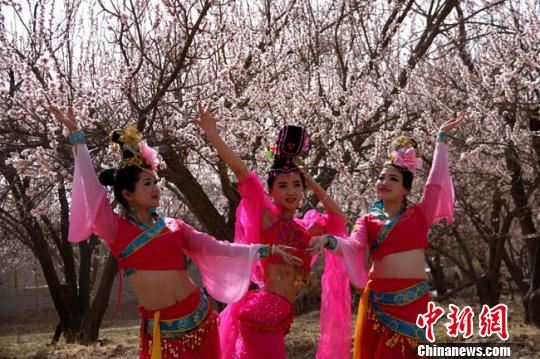 资料图。2016年4月，参加敦煌李广杏花节演出的演员在杏花园中拍照。　张晓亮 摄