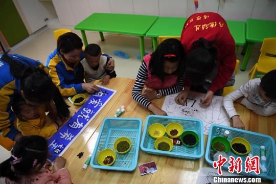 4月1日，大学生志愿者在老师的指导下和自闭症患儿一起制作手工画。　张斌　摄