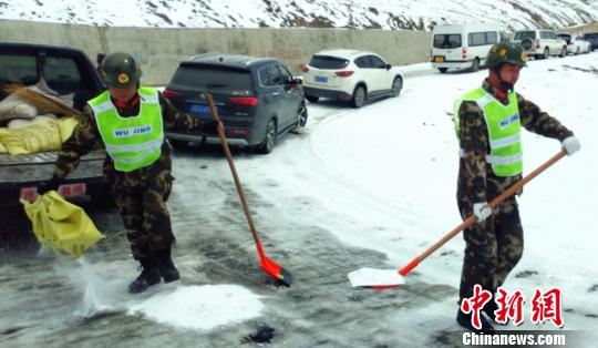 武警某部交通三支队驻左贡县中队官兵向结冰路面抛撒工业盐 路凯 摄