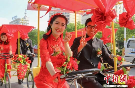 2018年5月4日，甘肃庆阳市54对新人自觉抵制高价彩礼，以低彩礼、零彩礼的实际行动引领健康、节俭、文明婚嫁新风，图为新人踏花车在市内出游。（资料图）　陈飞　摄