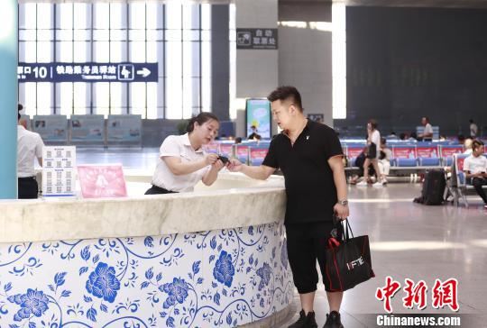 南昌车站“红土情”服务台工作人员李军正在服务旅客。　张杰 摄