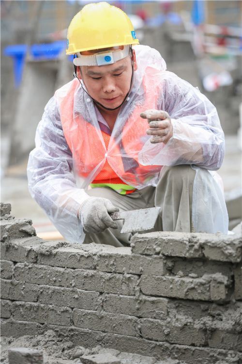 工人小心翼翼的把砖垒在水泥上