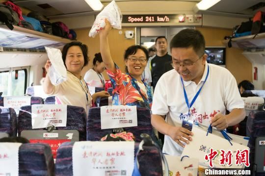 洪洞县文物旅游管理服务中心主任李晋豪在专列上向游客发放“洪洞印象”礼包。　王培基 摄