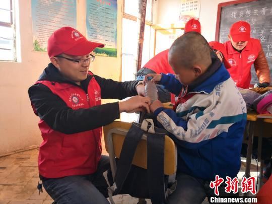 樊恒东(左)给甘肃榆中县北山的魏家台教学点小学生送学习用品。　许岗 摄